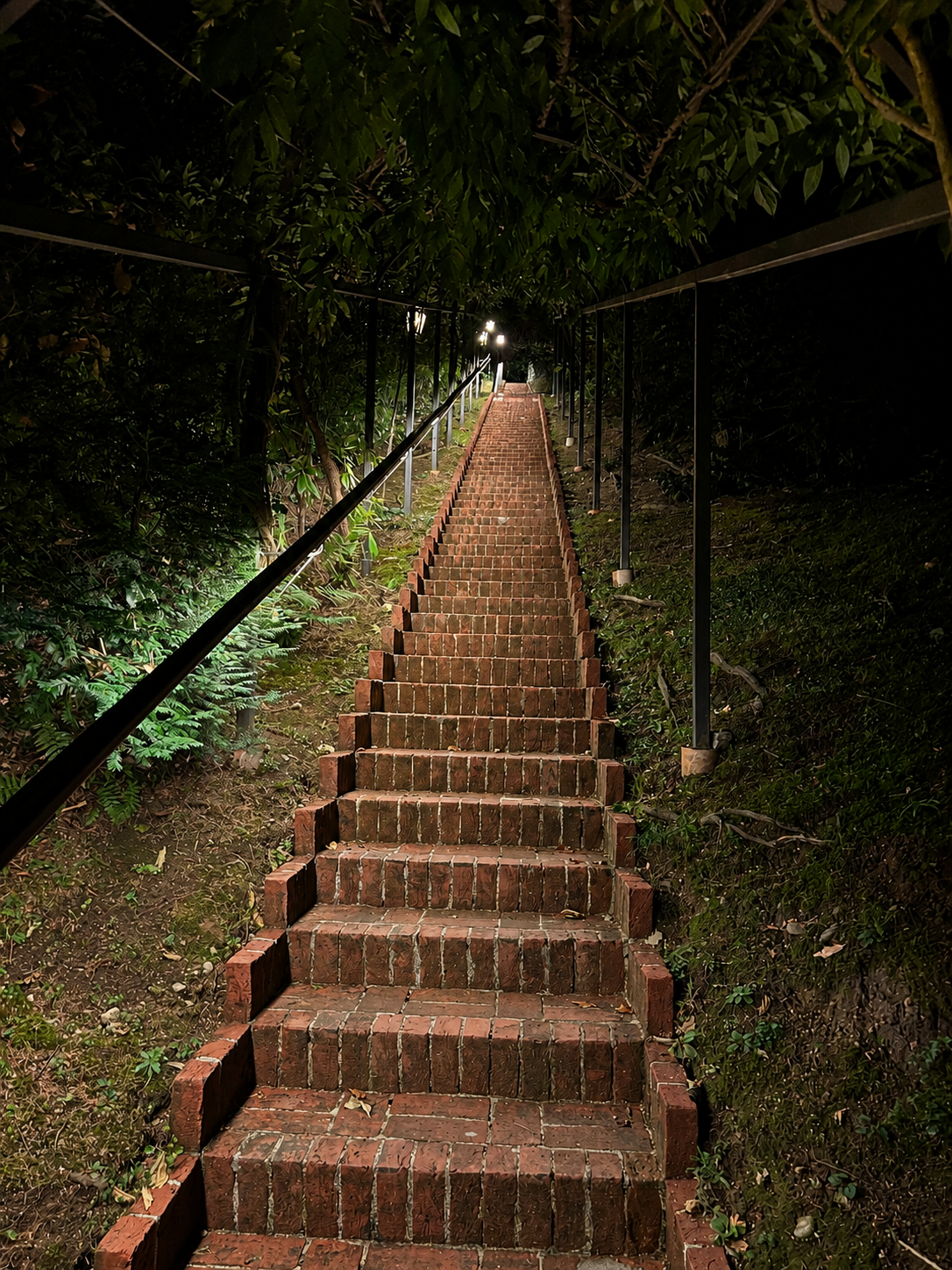Beleuchtete Backsteintreppe im Park der Villa La Collina bei Nacht